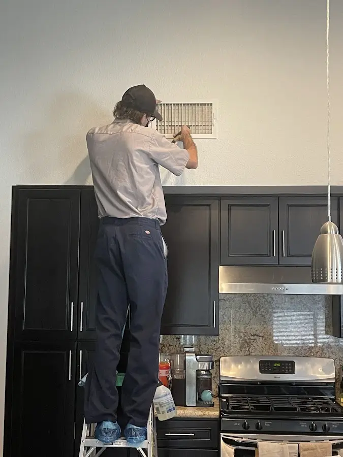 Technician inspecting an air vent during HVAC service in Kenner